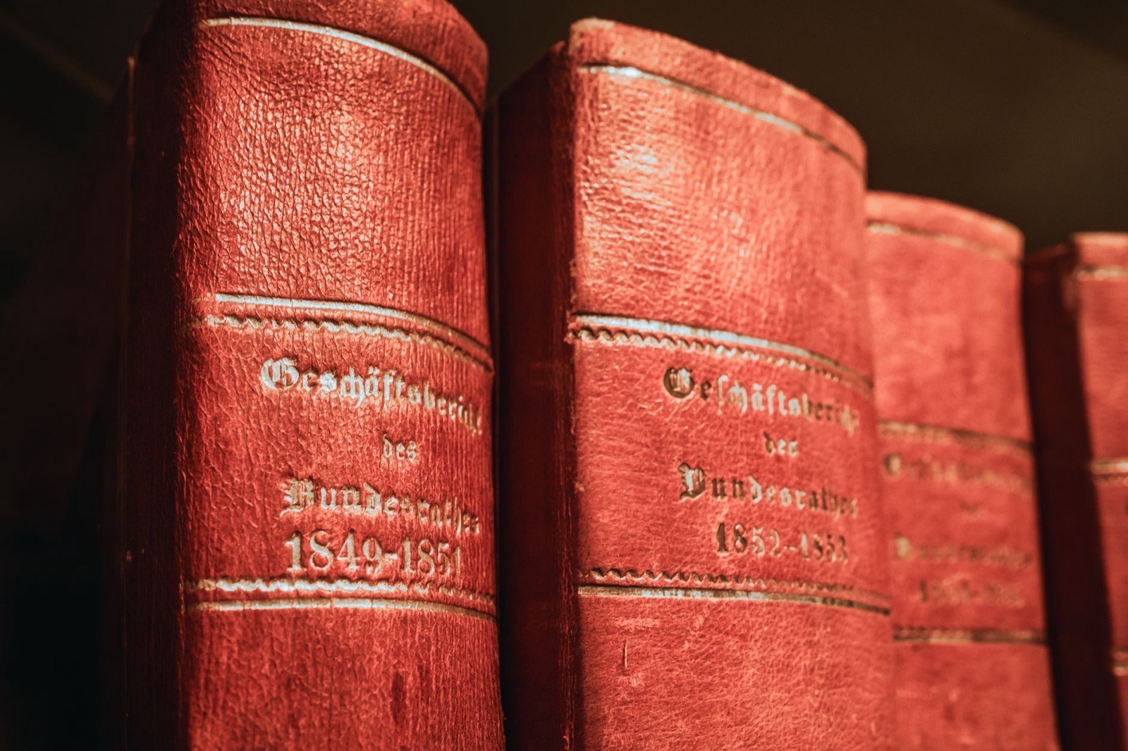 Red leather bound volumes of nineteenth-century official reports on a shelf.