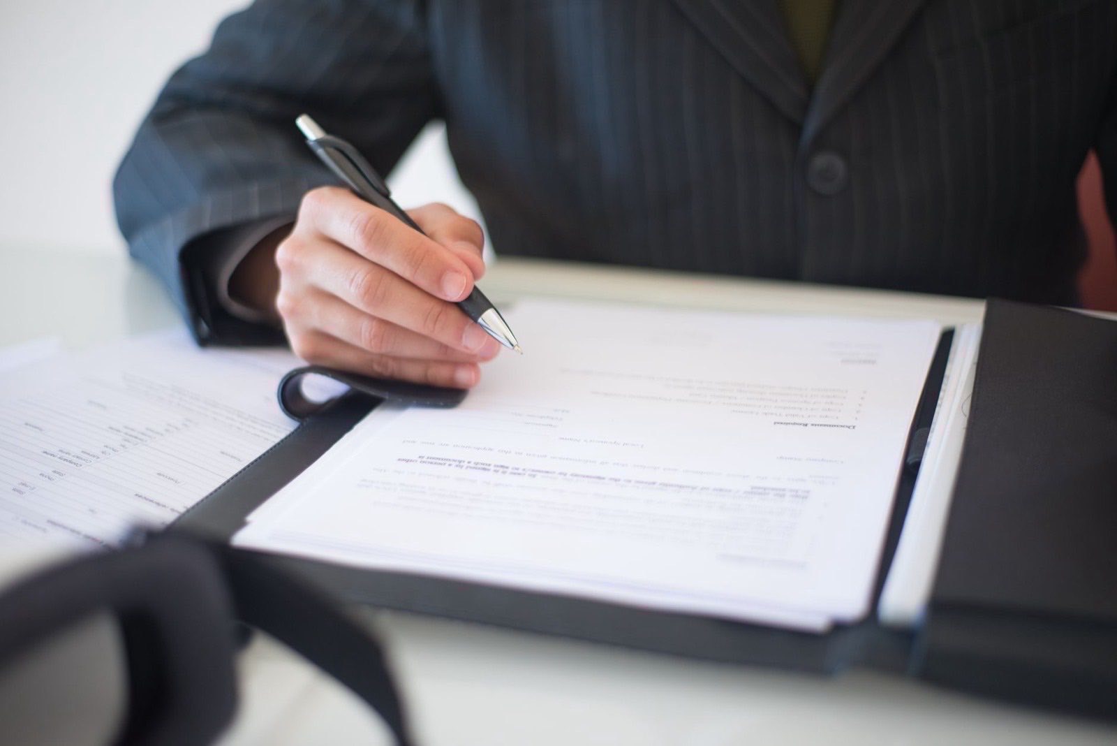 A document and a pen on a table with nobody present.